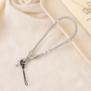 Macro detail of silver rhinestone phone charm strap with sparkling crystals and metal clasp