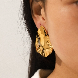 Irregular 18k gold hammered texture stainless steel earrings shown on a model