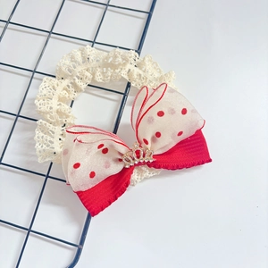 Detail of red bow baby headband with lace strap and a small gold rhinestone crown