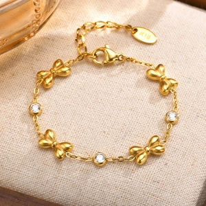 Détail d'un bracelet doré à nœud avec zircons en cœur sur un support en lin fin