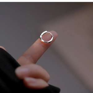 Close-up of minimalist s925 silver hoop earring held by fingers showing small size