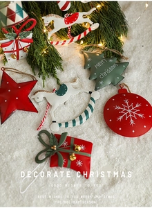 Detailed view of colorful tin Christmas ornaments like stars and trees on snowy branches