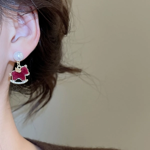Close-up of red flocked rocking horse earring with pearls and diamonds on model ear