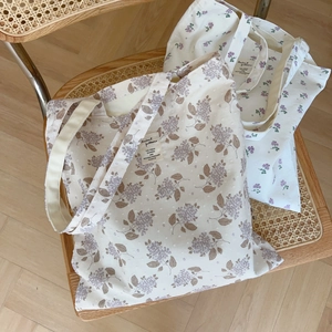 Detail of floral canvas tote bags with lavender prints on a woven chair in natural light