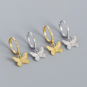 Vista detallada de pendientes de mariposa en plata y oro con alas de metal de textura fina