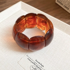Detail of amber tortoiseshell resin cuff bracelet with polished texture on a tray