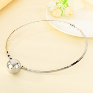 Polished silver metal collar necklace with a bold spherical pendant on a soft beige fabric