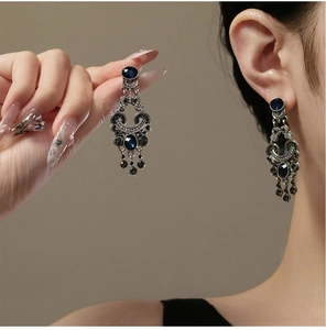 Macro shot of vintage silver earrings with blue crystals and dark tassel pendants