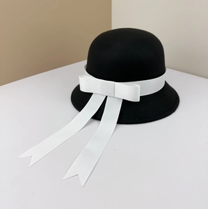 Close-up of black wool felt cloche hat with a large white grosgrain bow detail