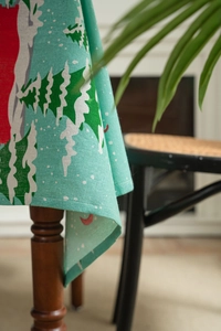 Detail of mint green linen Christmas tablecloth with snowy trees and red motifs