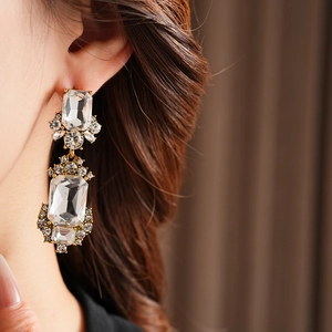 Close-up of vintage geometric square gold earrings with clear crystals on model's ear