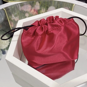 Close-up of a red satin drawstring storage pouch on a white mirrored tray with reflection