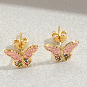 Detail of pink butterfly earrings with gold plating and colorful gemstones on white surface