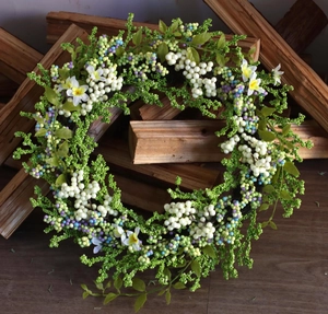 Detail of artificial berry wreath with green leaves and colorful berries on a wood background