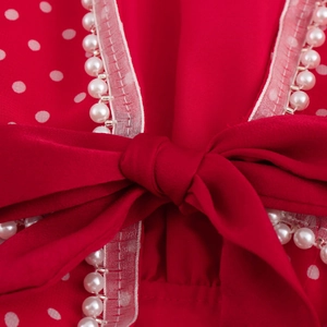 Abito rosso a pois con scollo a V, grande fiocco e bordo elegante in perle sintetiche