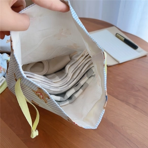 Detailed shot of striped bear pouch storage capacity with folded cotton clothes inside