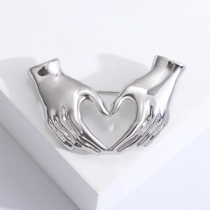 Minimalist silver heart hands brooch in polished metal for sweaters and coats