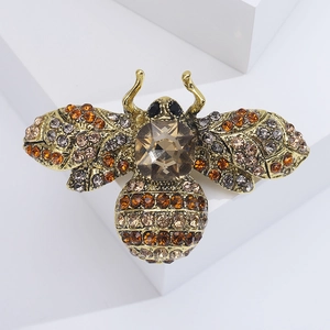 Detail of vintage bronze bee brooch with amber rhinestones on white geometric base
