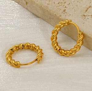 Close-up of gold-plated twisted hoop earrings with elegant texture on a stone background