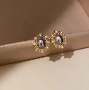 Macro shot of vintage gold earrings with oval iridescent opal and pearl halo detailing