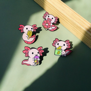 Détails de quatre pin's axolotl en émail avec donut et bubble tea sur fond vert doux
