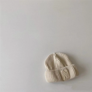 Close-up of oatmeal ribbed knit beanie with letter N patch detail and thick folded cuff