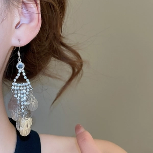Detail of long tassel earrings with sparkling rhinestones and silver leaf pendants