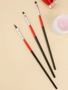 Detailed view of three professional nail art brushes with red and black wooden handles