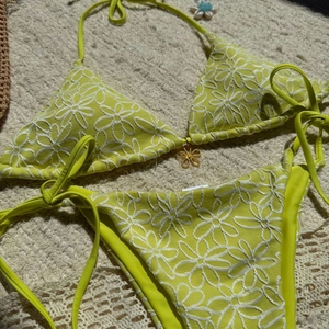 Detail of lime green floral bikini with golden flower pendant and side-tie design