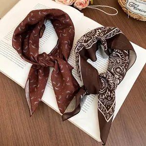 Elegant paisley silk scarf necklace with brown patterns over an open book setting