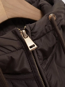 Macro detail of golden metal zipper and quilted fabric on the brown hooded parka jacket