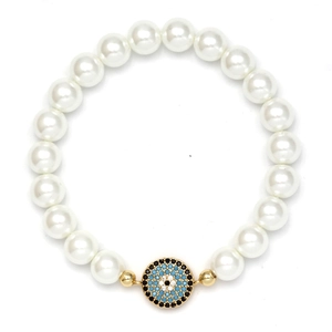Detail of beaded shell pearl bracelet with a blue evil eye charm in gold setting