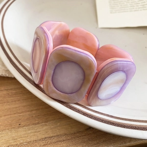 Detail of resin stretch bracelet showing purple marble texture in a white ceramic dish