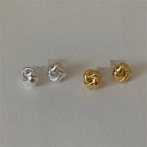 Dettaglio di orecchini a nodo intrecciato in oro e argento con elegante finitura lucida