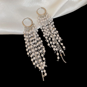 Detail view of long tassel earrings with white pearls on silver-tone metal chains