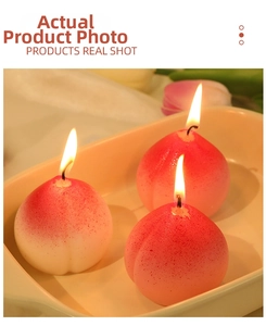 Detailed view of three realistic peach-shaped scented candles in a ceramic tray