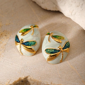 Close-up of gold-plated dragonfly earrings with blue marble enamel and green wings