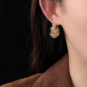 Detail of gold hollow twisted C-shaped earrings on model with high gloss finish