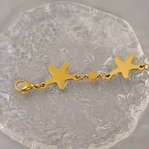 Macro detail of gold starfish pendant bracelet on textured glass with lobster clasp