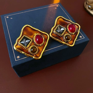 Détail de boucles d'oreilles vintage dorées avec émail ambré et pierres colorées