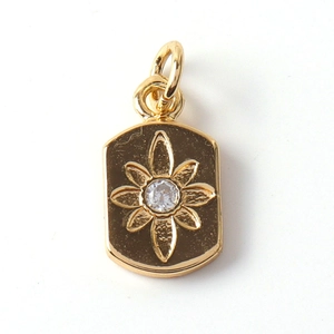 Detail of a gold-plated flower pendant with white zircon inlay on a rectangular base