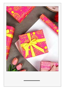 Detail of pink birthday wrapping paper with cake patterns and yellow ribbon bow