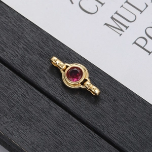 Elegant gold bracelet link with a brilliant red round zircon on a minimalist paper background