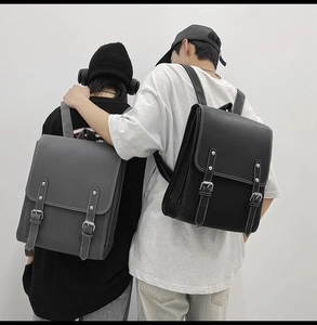 Rear view of couple wearing minimalist vintage leather backpacks in grey and black