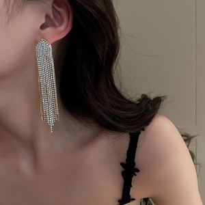 Close-up of long tassel earrings with sparkling crystals on female model for party look