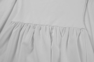 Gros plan du tissu blanc montrant les coutures de taille et les détails plissés