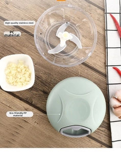 Detail view of manual garlic chopper with sharp stainless steel blades and green pull lid