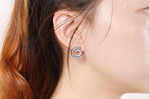 Close-up of model wearing C-shaped stainless steel stud earrings with shimmering stones