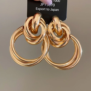 Gros plan de boucles d'oreilles pendantes à cercles entrelacés dorés avec fini poli
