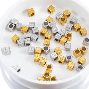 Makro-Detail von 7mm quadratischen Gold- und Silber-Buchstabenperlen für DIY-Halsketten